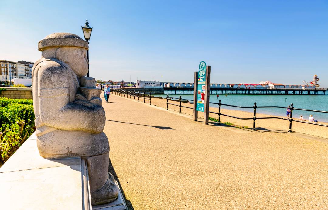 Stone Statue On A Promenade With Railings Next to The Sea